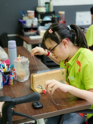 An S P D Artisan Collab leather apprentice sewing a key fob