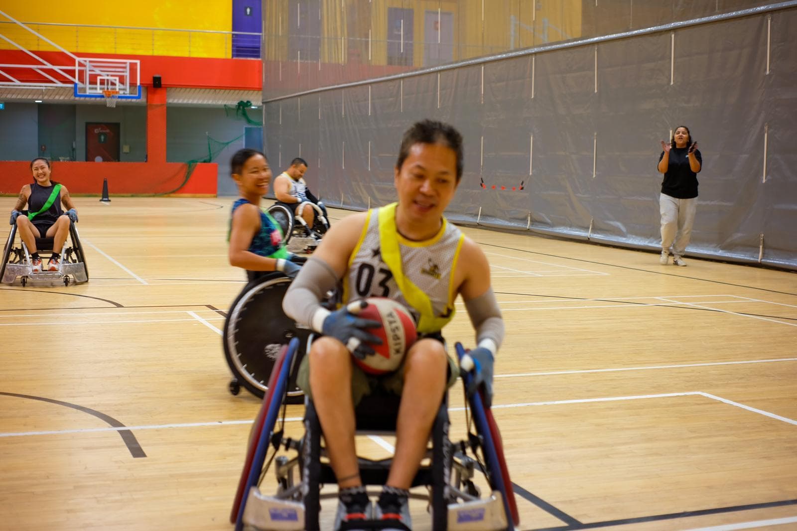Mr Wong playing wheelchair rugby as Mdm Nooraini cheers on in the background.