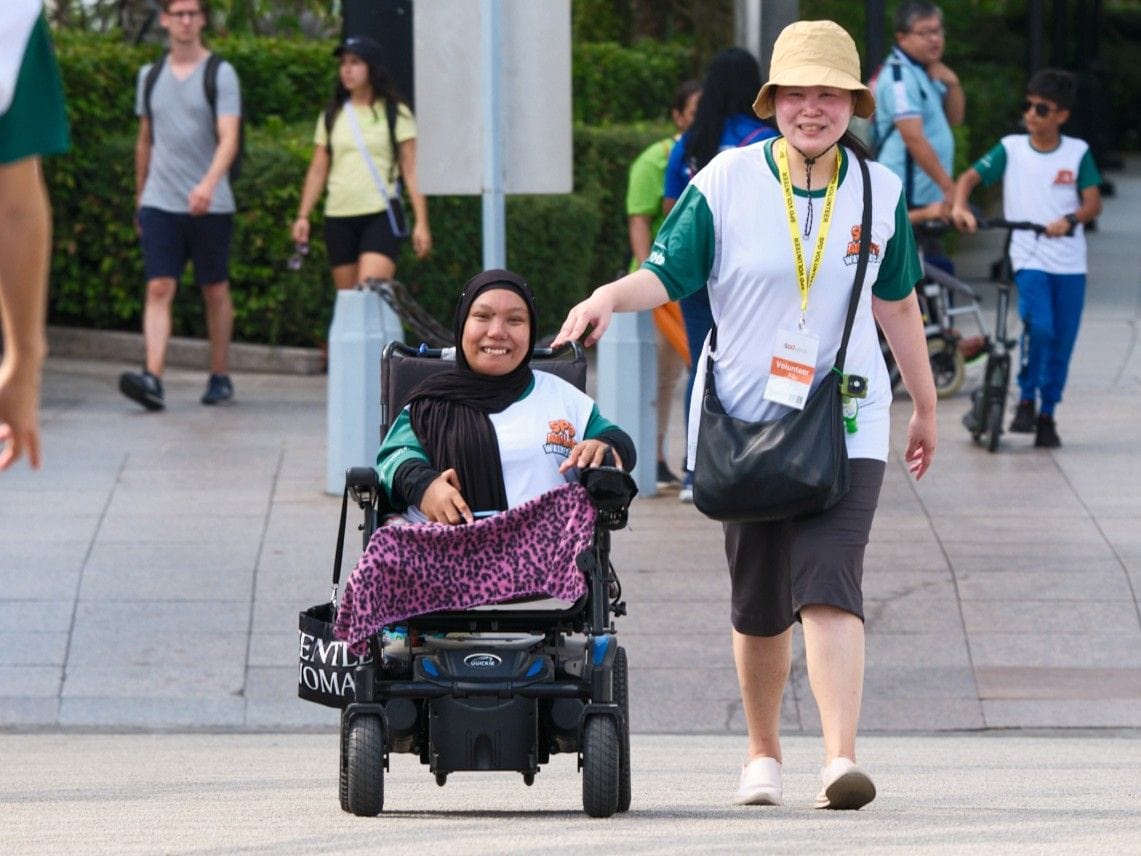 What you need to know about choosing a wheelchair 5 A young woman controlling her wheelchair using a joystick, another lady walks beside her.