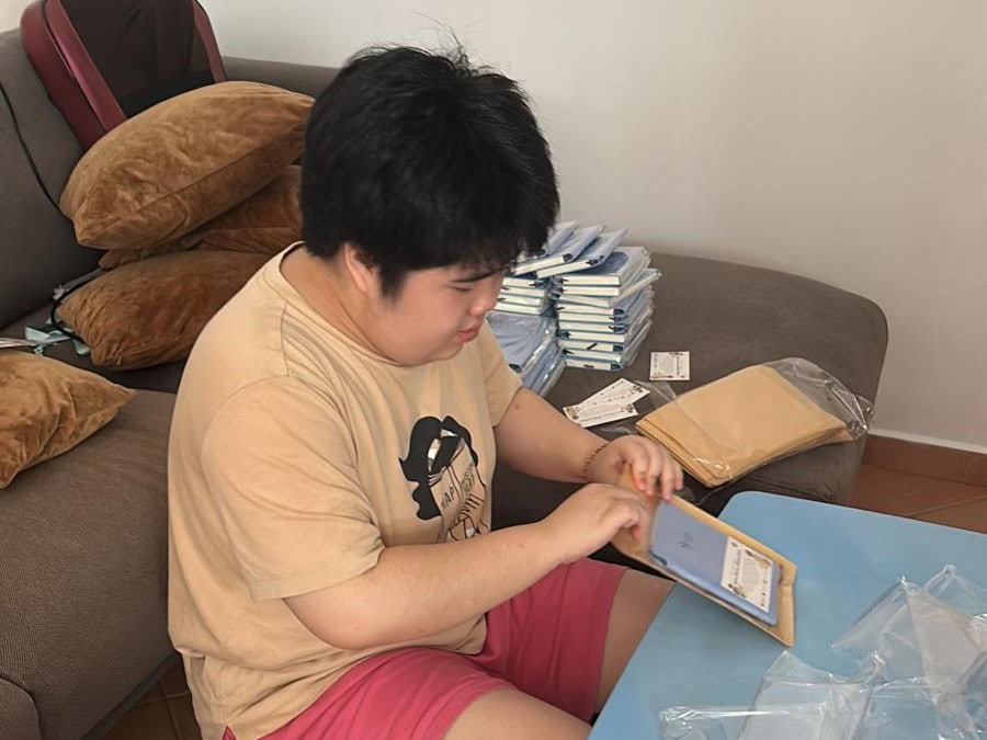 World Autism Awareness Day: A Call for Understanding and Inclusion 2 Gek Huee putting notebooks into plastic packaging.