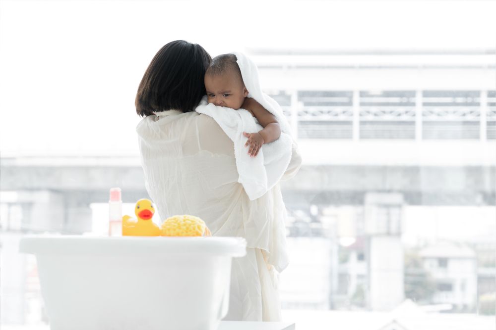 Turning Shower Time into a Positive Learning Experience for Children 1 A mother holding a young child, back against a small bath tub.