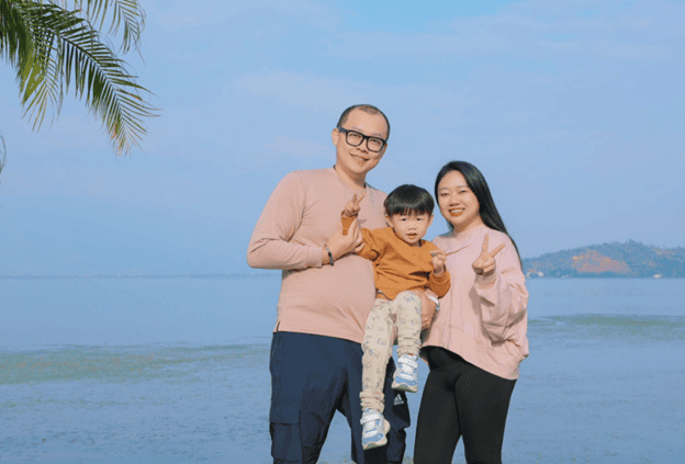 Evan with his wife and son with the ocean in the background.
