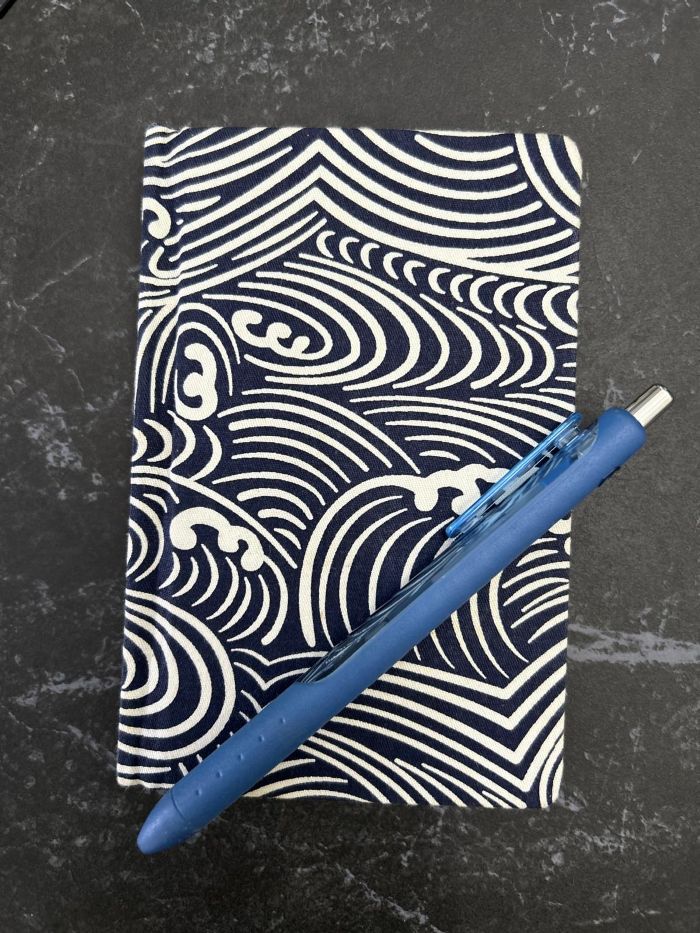 What’s inside their bags? - Employment support professionals' edition 1 Andrea's notepad woith blue Japanese-inspired wave design, and a blue pen