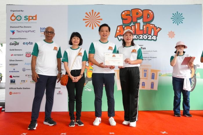 Educating with Heart: How Wang Learning Centre is Shaping a Kinder Generation 3 Mdm Wang at the S P D Ability Walk 2024 receiving a token of appreciation from G O H Mr Alvin Tan, joined by S P D's C E O Mr Pal and S P D President Ms Ong