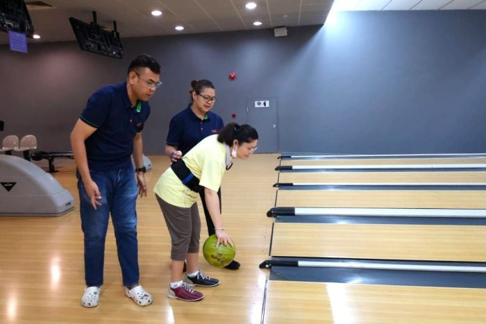 Vanessa and a fellow D W W staff guiding a D W W client in bowling.