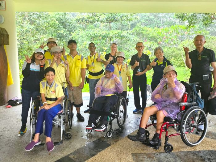 Vanessa with the D W W clients and volunteers, some in raincoats, smiling happily