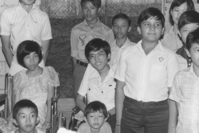From the CEO’s Desk: Philip’s journey and what lasting impact means at SPD 2 Black and white photo of a school-aged Philip seated in his wheelchair and smiling amongst a group of students.