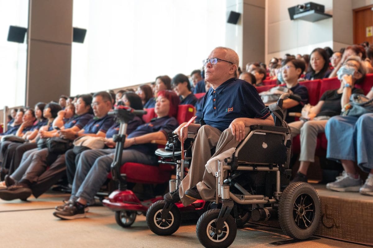 From the CEO’s Desk: Philip’s journey and what lasting impact means at SPD 5 Philip and fellow S P D staff listening intently inside an auditorium.
