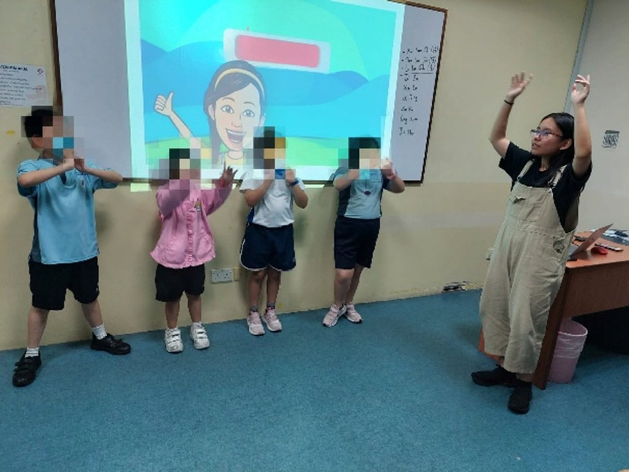 Turning Self-Doubt into Purpose, Youth with Vision Loss Hopes to Help Others Find Strength 2 Cindy as a volunteer teaching assistant leading a group of 4 children in school uniforms in a song session