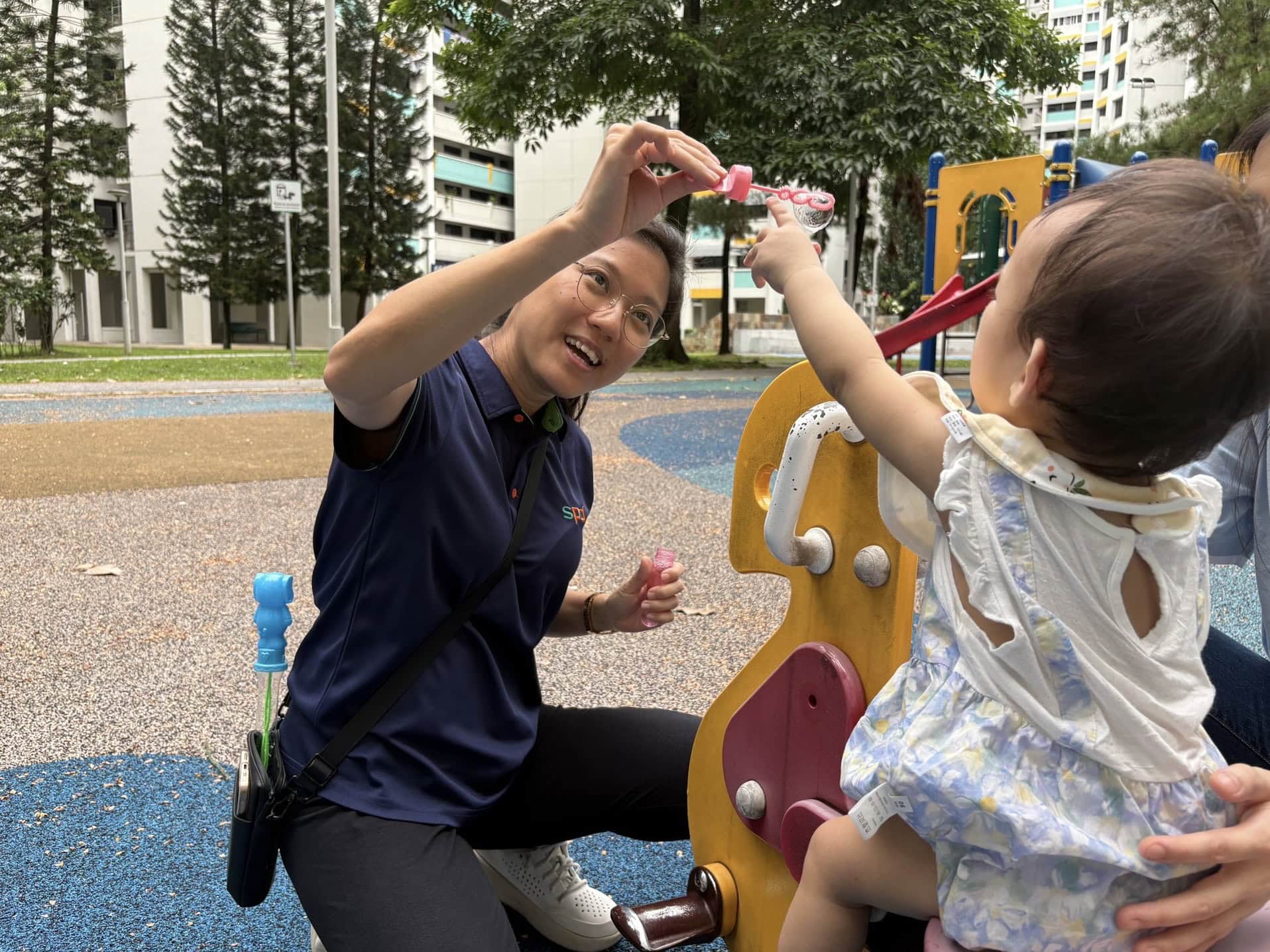 Jia Yi engaging with a toddler in an outdoor playground