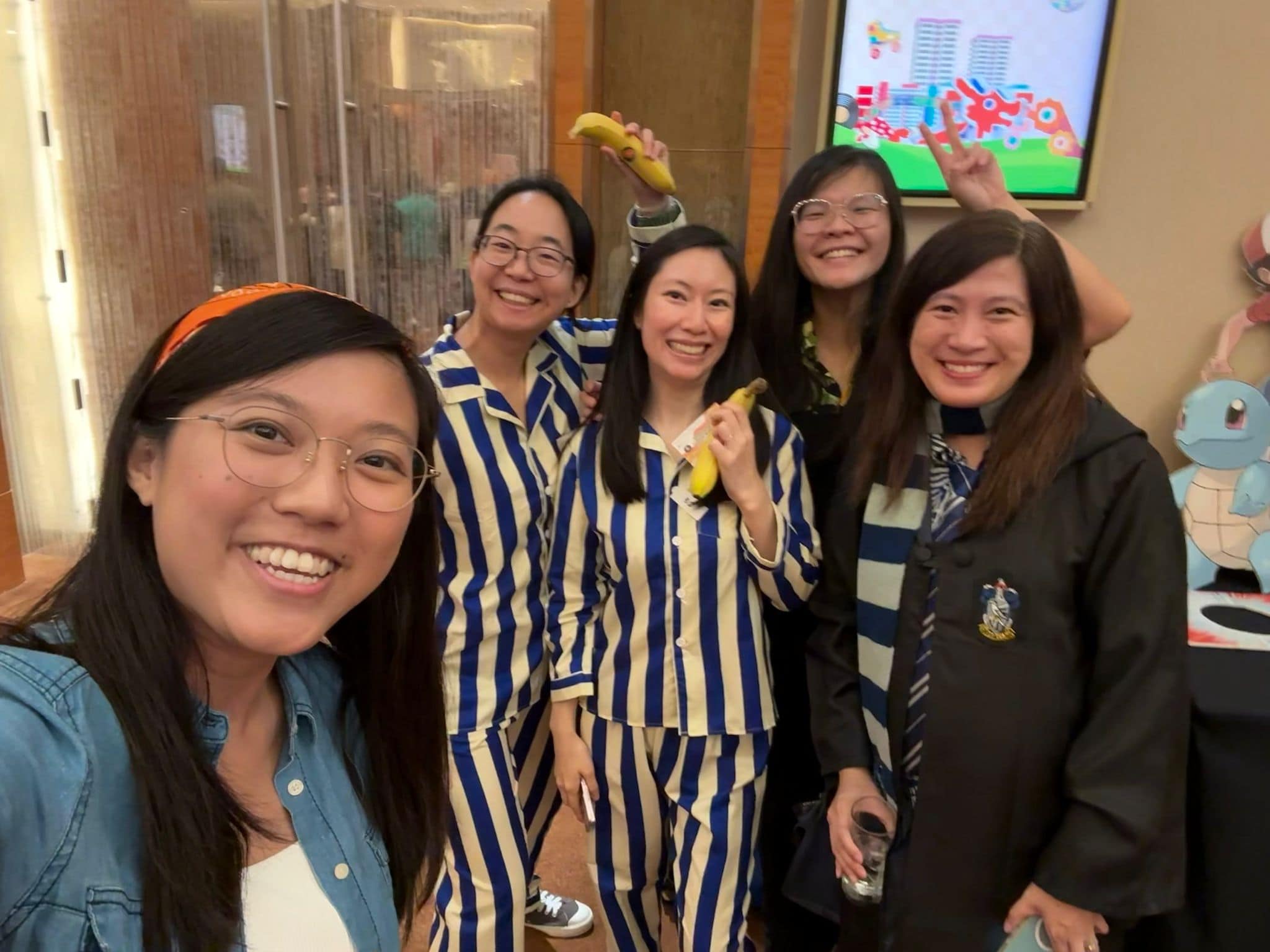 Power of Care – Finding voices, building confidence 1 Qingwen and a colleague dressed in blue striped pajamas and each holding a banana, to the theme of Bananas in Pajamas. Beside them are 3 other colleagues dressed up to the Staff Day theeme of 'When we were young'.