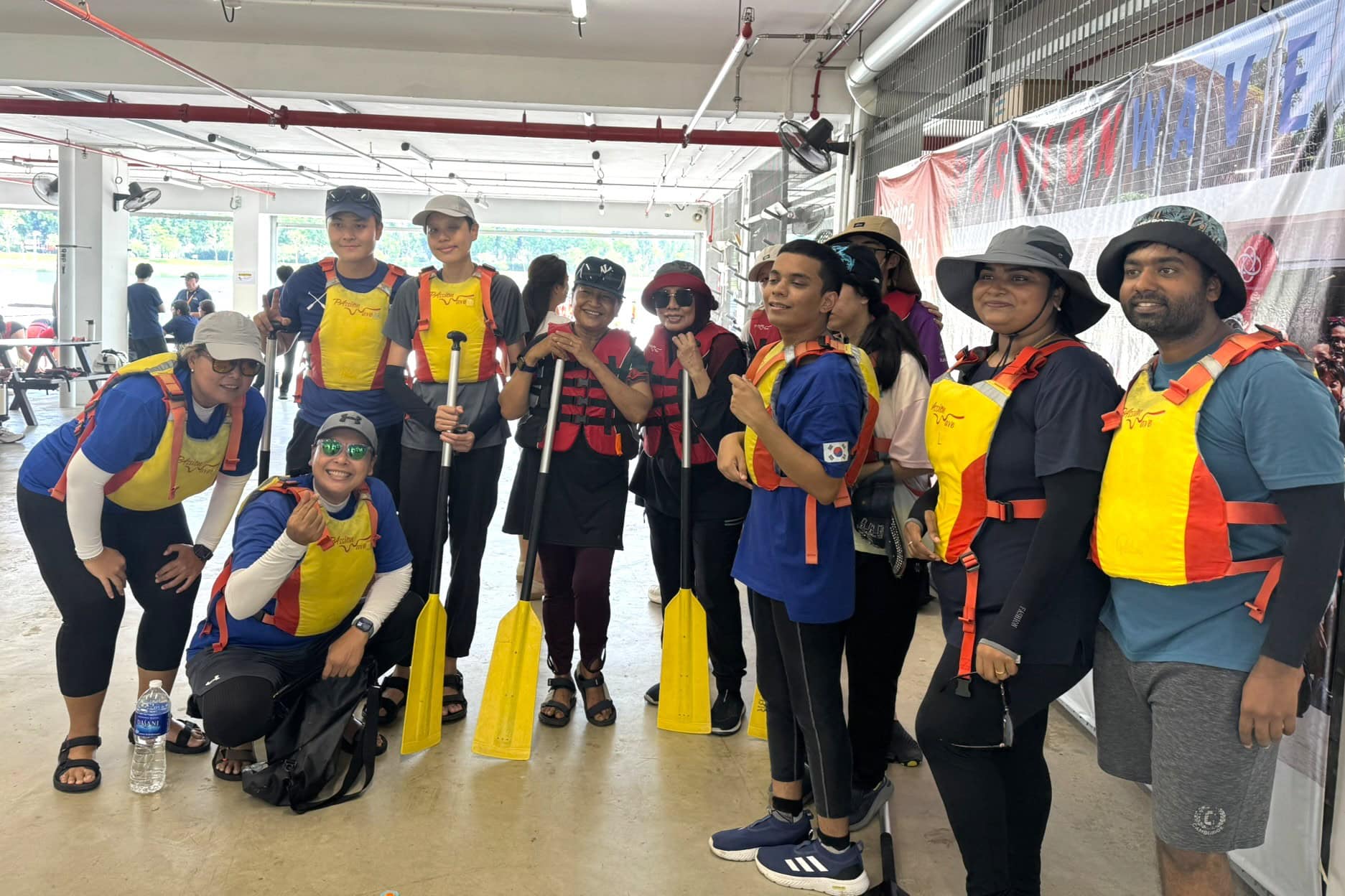 Strength in Community: She Came to Help Others and Found Support Herself 5 Sindhu with the clients and fellow volunteers at the dragon boat event. All of them have life vests on, and some have oars in hand.