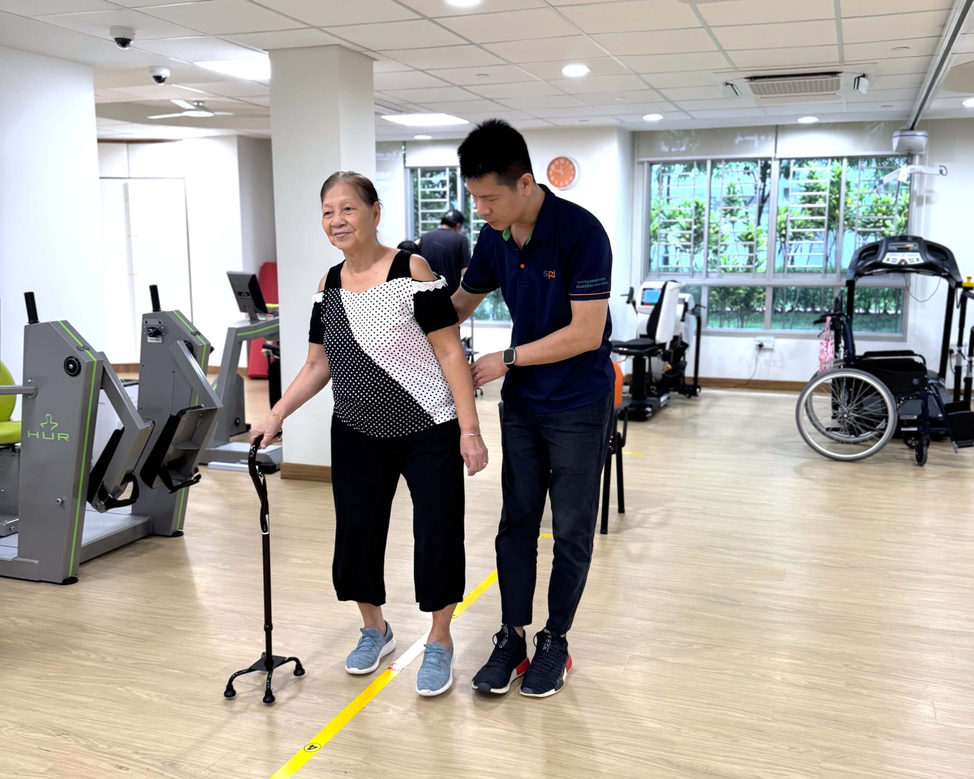 Power of Care – Holistic Care Through Collaboration 1 Winson assisting a senior who is walking using a walking stick as support.