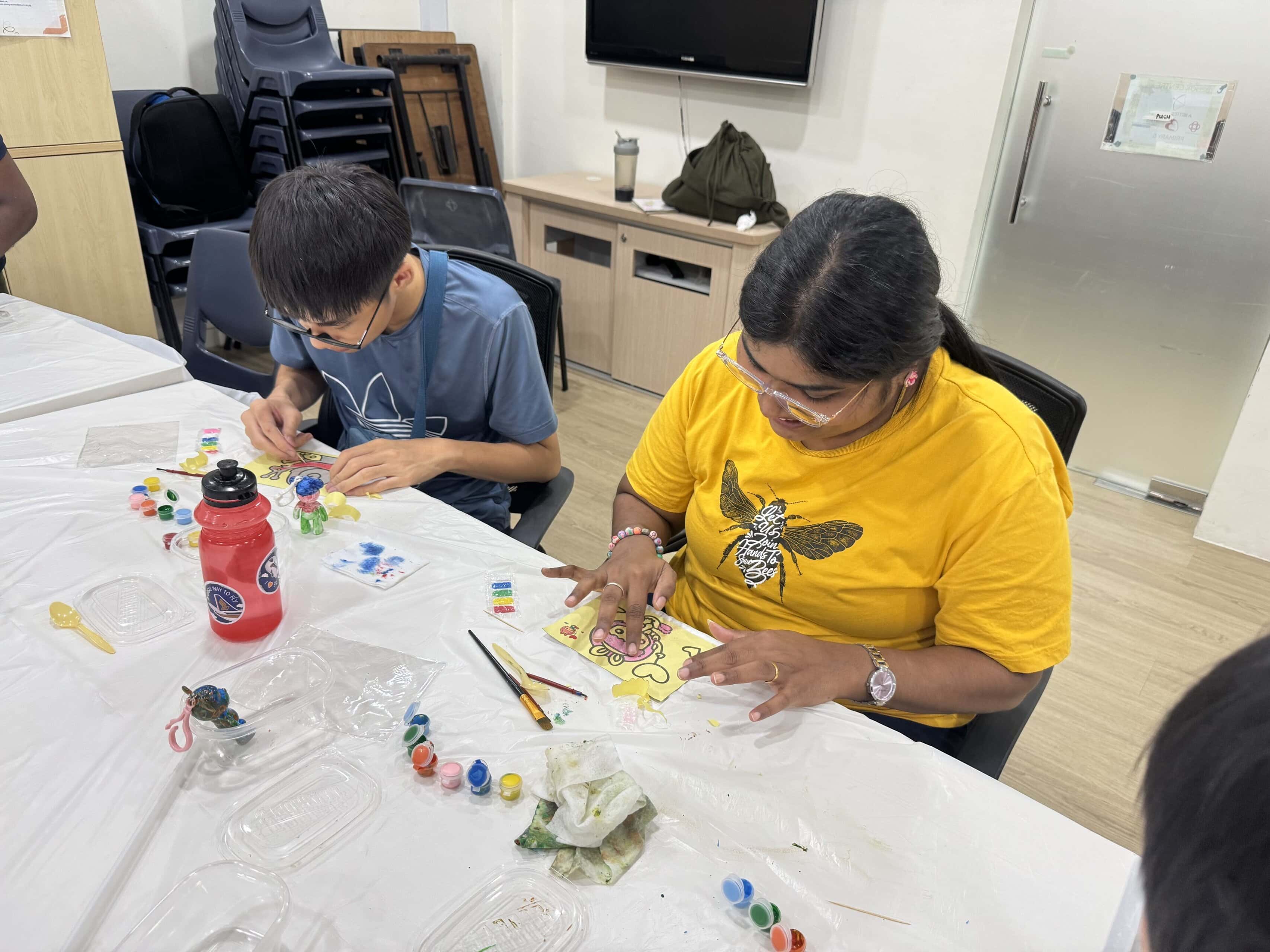 Strength in Community: She Came to Help Others and Found Support Herself 2 Sindhu engaging an E S H Tampines client during a craft session that involves painting within lines.