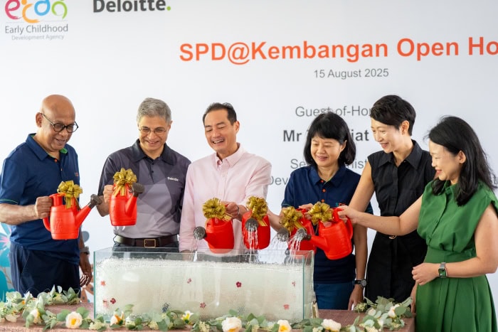 Guests at S P D Kembangan open house each using their red watering can to pour water into fish tank filled with bubbles. Includes Mr Abhimanyau Pal, SPD C E O; Mr Shariq Barmaky, Country Managing Partner, Deloitte Singapore; Guest-of-Honour Mr Tan Kiat How; Ms Ong Toon Hui, S P D President; Ms June Wong, Director, Early Childhood, ECDA; and Ms Lee May Gee, C E O, S G Enable. 
