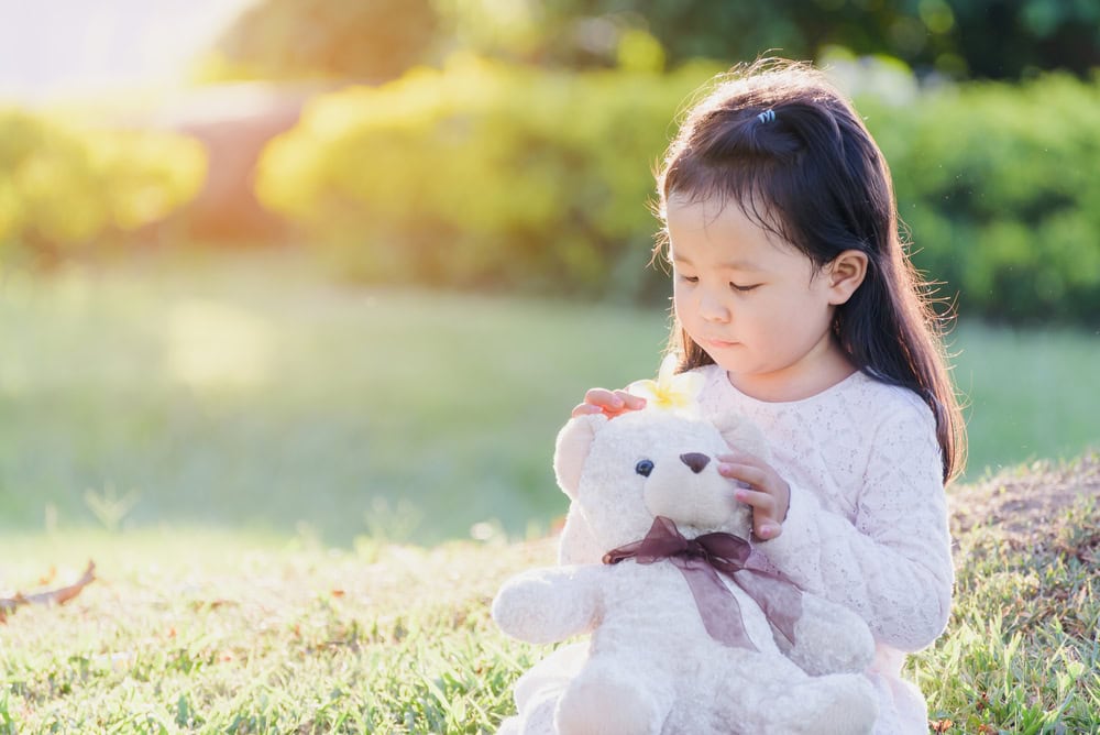 A young girl holding a teddy bear