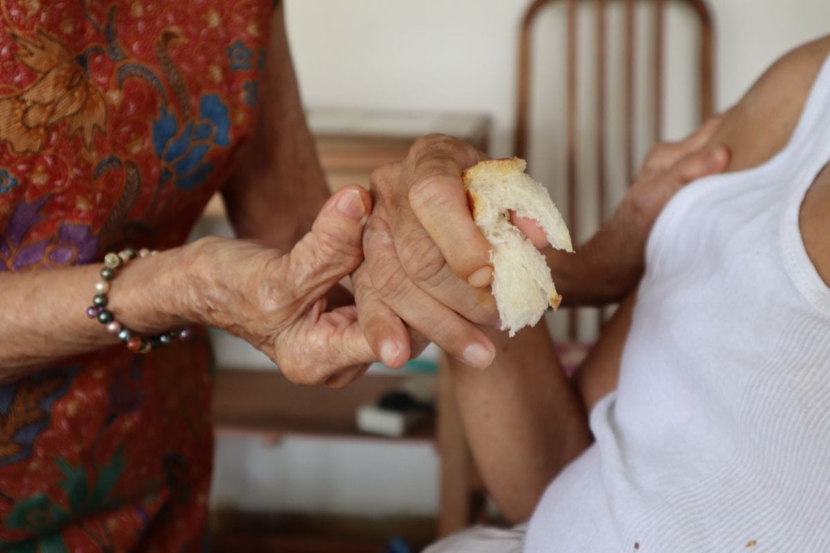 A Heart That Never Grows Old: Auntie Molly’s volunteer journey with SPD 7 Auntie Molly's hands cupping her youngest son Mr Lee's as he holds onto a piece of bread.