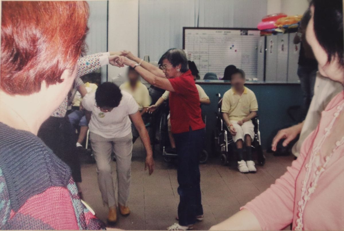 A Heart That Never Grows Old: Auntie Molly’s volunteer journey with SPD 4 An old photo of Auntie Molly at the D A C playing 'London Bridge is Falling Down' with the clients.