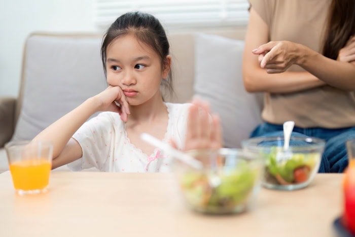 Simple strategies for happier mealtimes 2 A child looks away and pushes away a bowl of vegetables