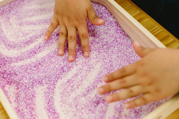 Little hands playing on a purple salt tray