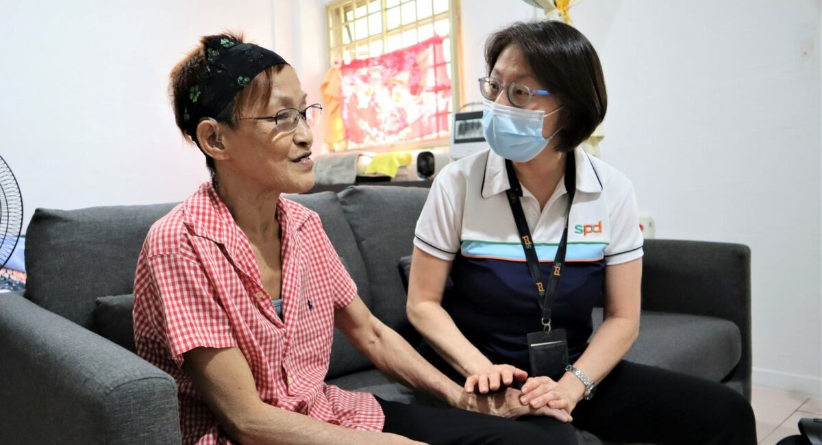 An S P D professional places her hands on an elderly lady's and listening to her speak