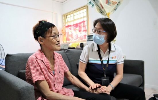 An S P D professional places her hands on an elderly lady's and listening to her speak