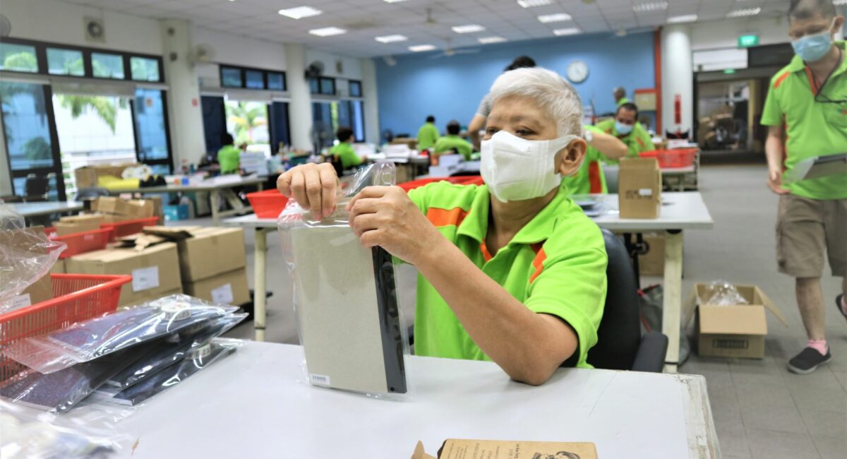 Sheltered Workshop trainee putting a plastic cover on a book