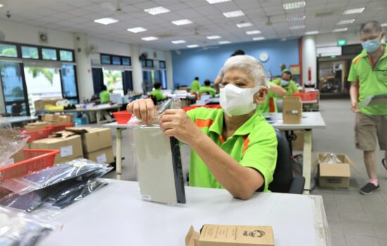 Sheltered Workshop trainee putting a plastic cover on a book