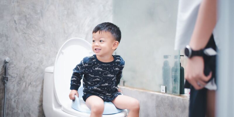 Boy sitting on toilet bowl