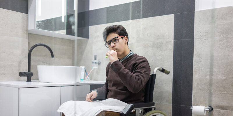 A wheelchair user brushing his teeth