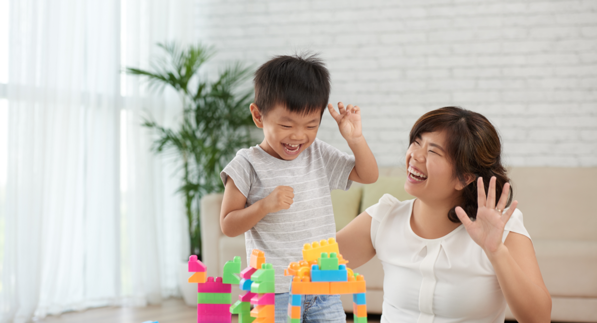 A woman playing multi-coloured blocks with a boy