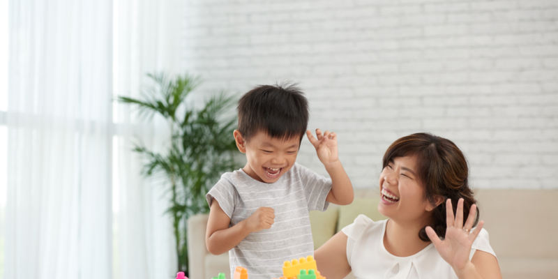 A woman playing multi-coloured blocks with a boy