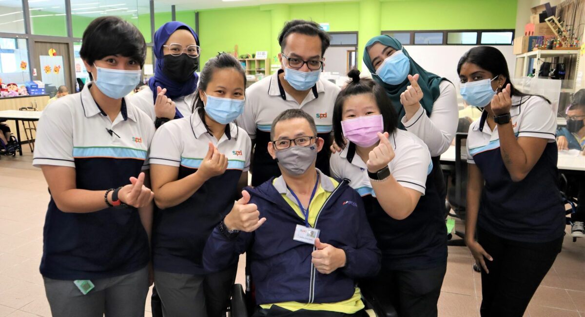 A group of staff with a wheelchair user posing for the camera