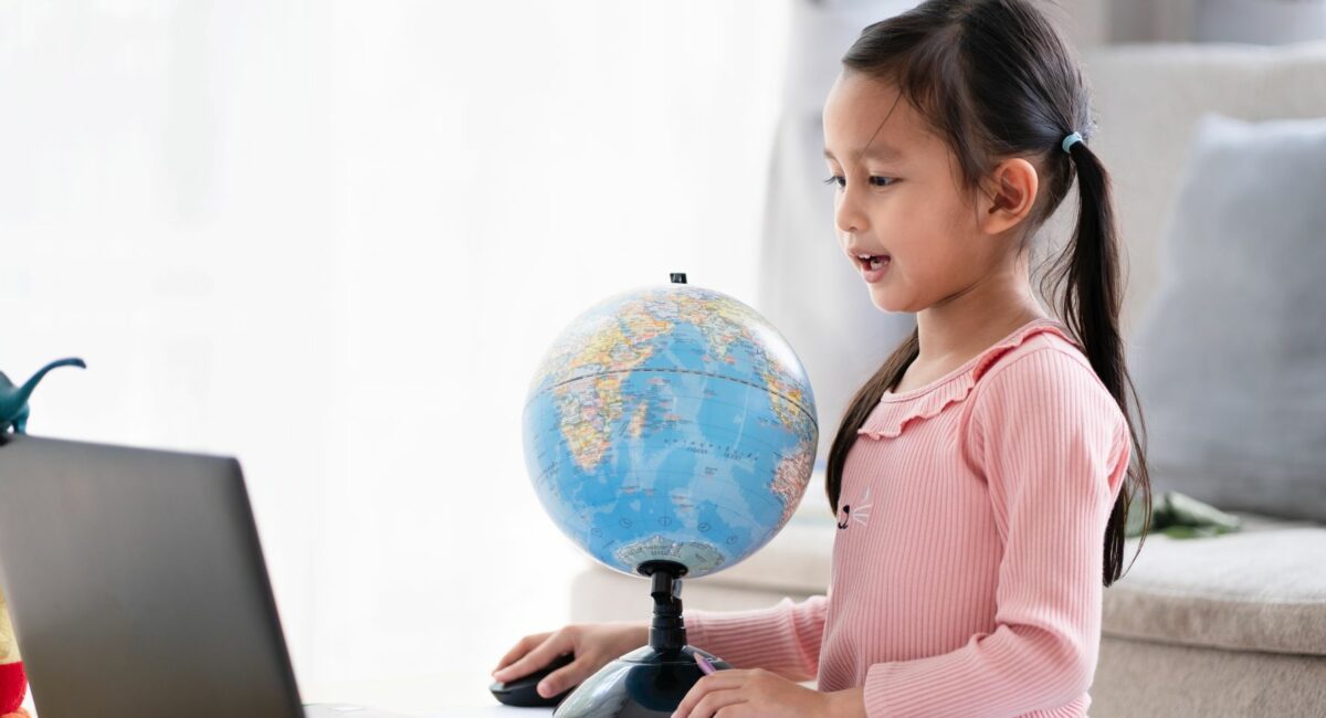 Girl looking at laptop and globe in front of her