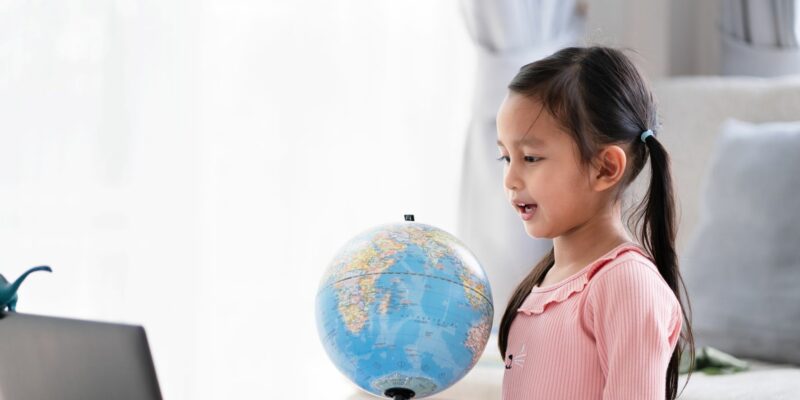 Girl looking at laptop and globe in front of her