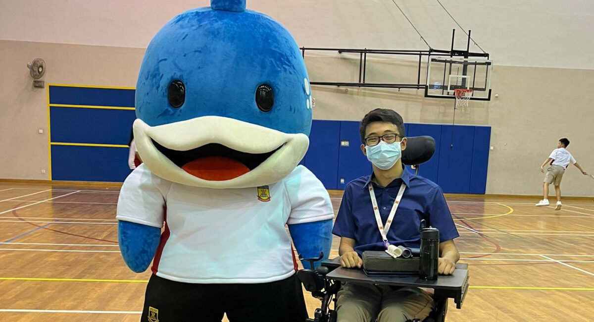 Mr Wong seated in his wheelchair beside a blue whale mascot