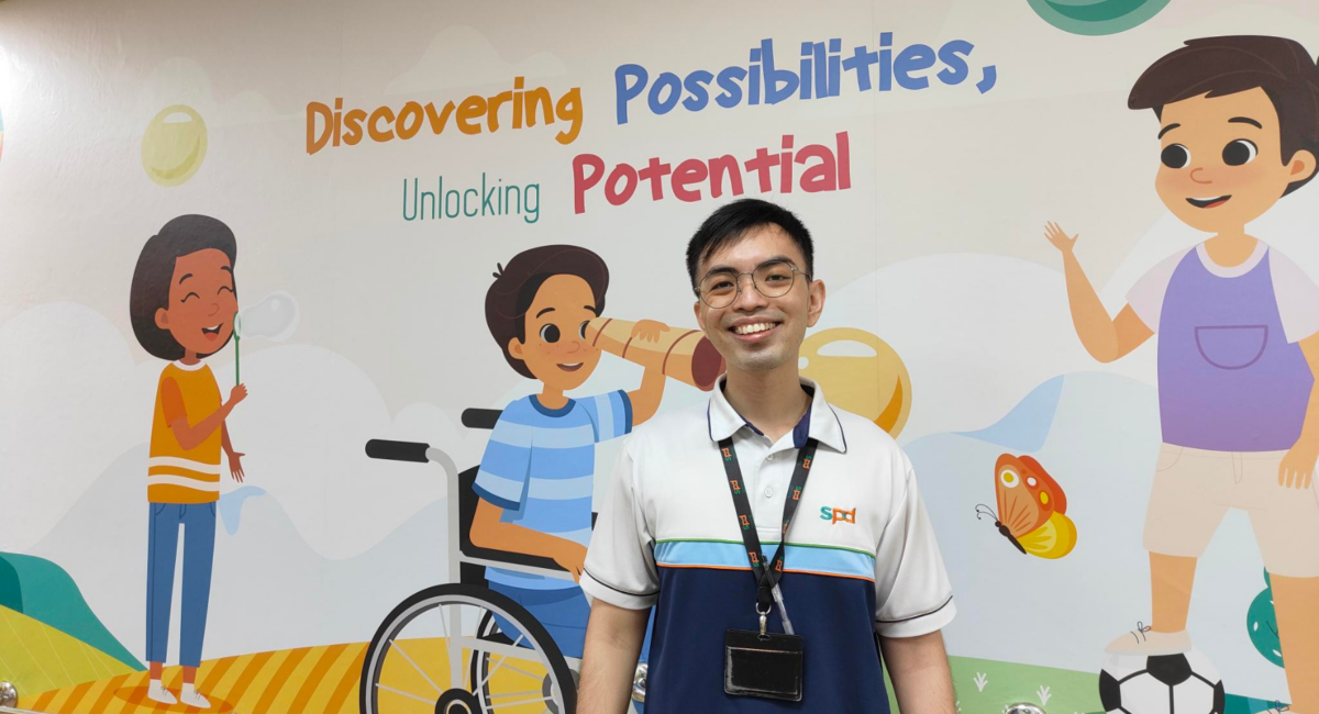 A man smiling and standing in front of a wall