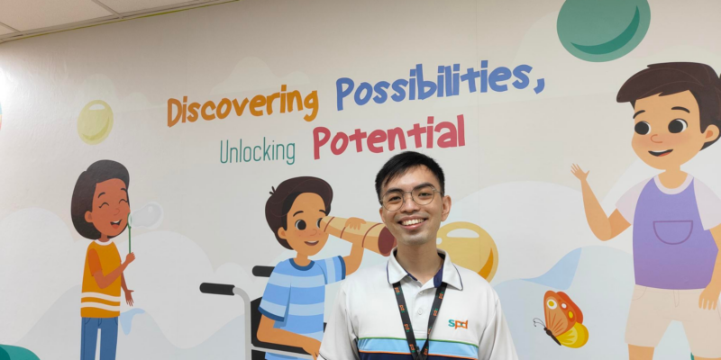 A man smiling and standing in front of a wall