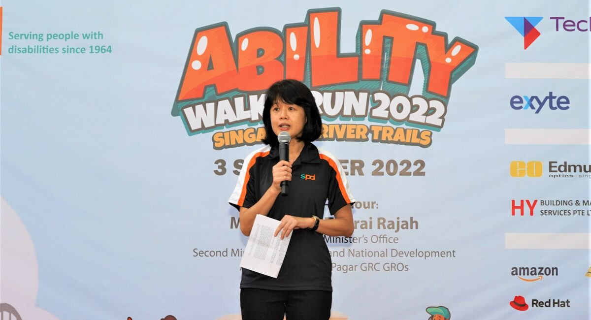 A lady holding a microphone and speaking on stage