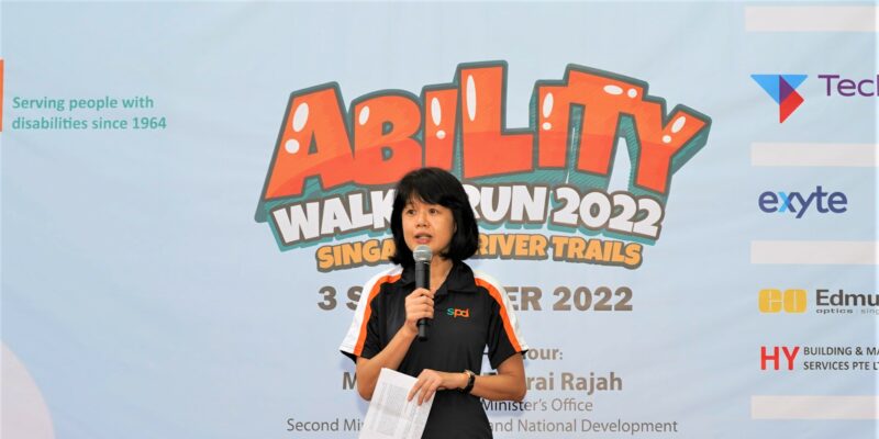 A lady holding a microphone and speaking on stage