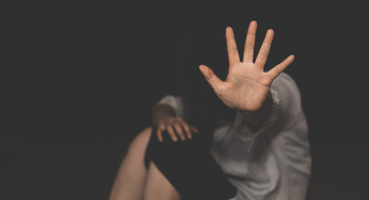 A person sitting on the floor, holding hand up to signify "stop"
