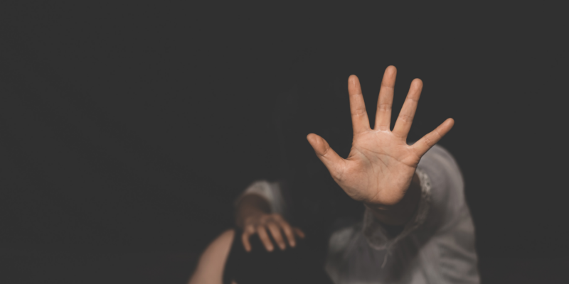 A person sitting on the floor, holding hand up to signify "stop"