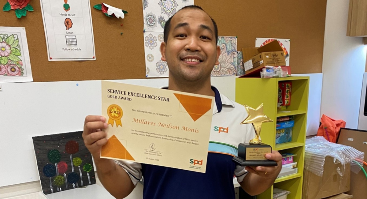Neilson holding the Service Excellence Award certificate and trophy