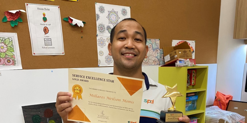 Neilson holding the Service Excellence Award certificate and trophy
