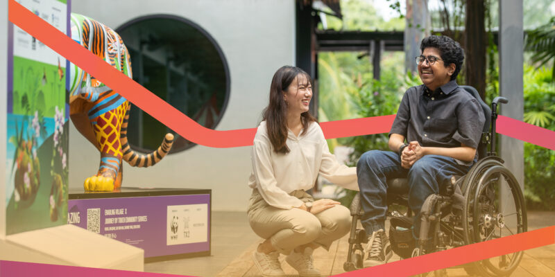 A volunteer positioning herself beside a wheelchair user, both smiling