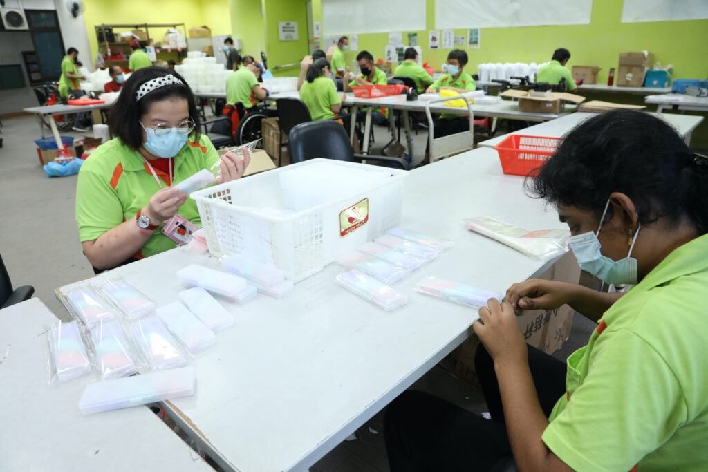 A group of S P D Sheltered Workshop trainees engaging in packing work