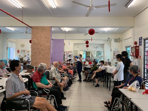 A group of elderly clients paying attention to Ruimin while she explains the group activity
