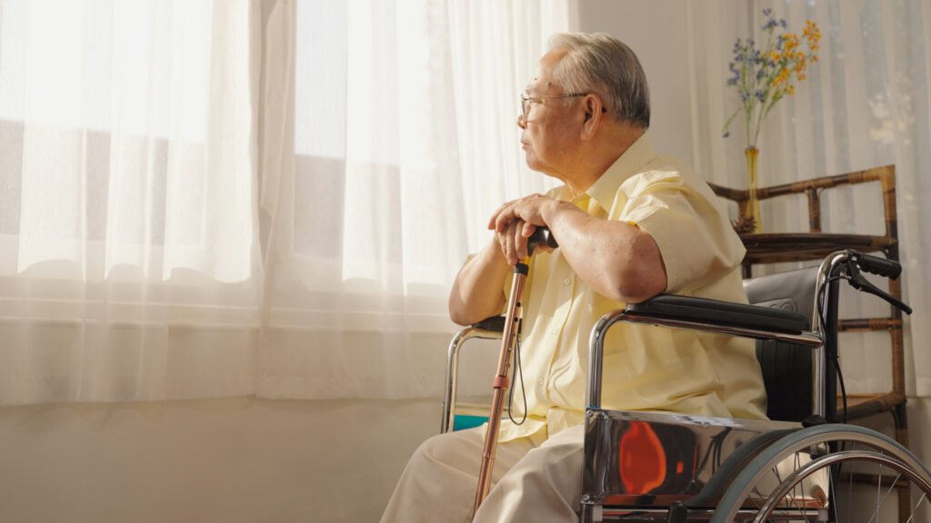 An elderly wheelchair user looking out of the window