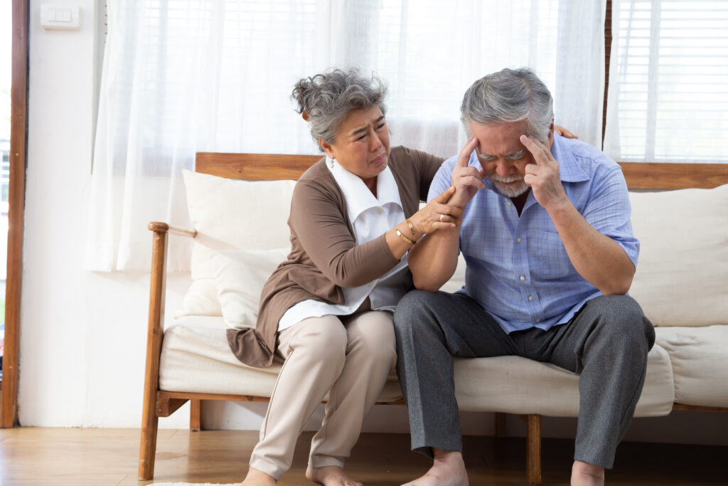 An elderly woman comforting an elderly man who has dementia