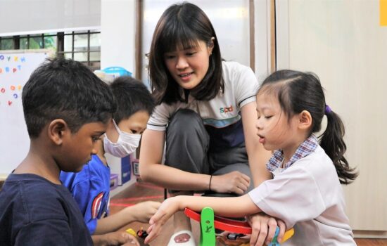 Speech therapist Danica looking on as 3 children play with building blocks